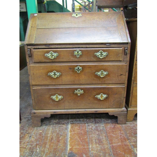 1468 - A George III country oak bureau of three long drawers, the fall flap enclosing the original stepped ... 