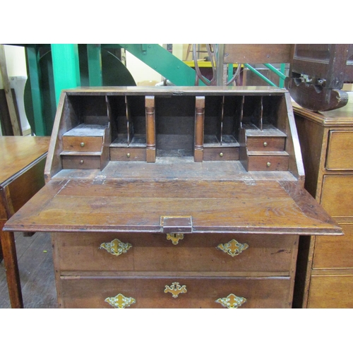 1468 - A George III country oak bureau of three long drawers, the fall flap enclosing the original stepped ... 