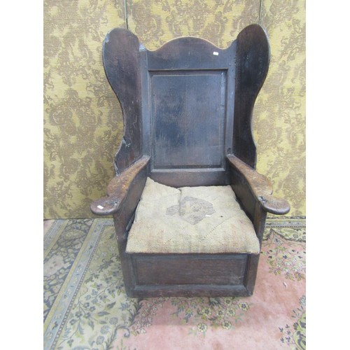 1536 - An 18th century oak lambing chair with fielded panel back and deep winged sides, the shaped arms ove... 