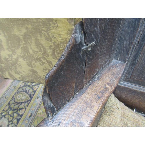 1536 - An 18th century oak lambing chair with fielded panel back and deep winged sides, the shaped arms ove... 