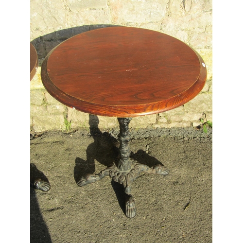 1053 - Three circular wooden topped pub tables raised on cast iron bases with swept paw feet, the tops appr... 