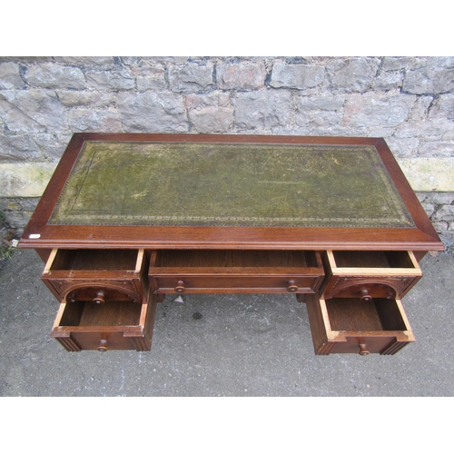 1191 - A reproduction oak writing table/desk with inset leather panel top over an arrangement of five friez... 