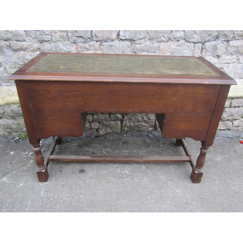 1191 - A reproduction oak writing table/desk with inset leather panel top over an arrangement of five friez... 