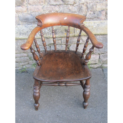 1271 - An antique stained elm and beechwood smokers bow elbow chair with turned spindle back and saddle sha... 