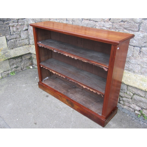 1300 - A late Victorian walnut floorstanding open bookcase with two adjustable shelves and set on a plinth,... 