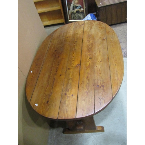 1161 - A rustic stained pine kitchen  table of oval form with boarded top and supports united by a central ... 