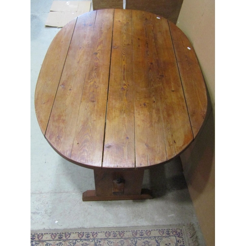 1161 - A rustic stained pine kitchen  table of oval form with boarded top and supports united by a central ... 