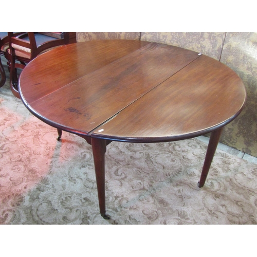 1250 - A Georgian mahogany oval dropleaf dining table raised on simple turned tapered legs with brass caps ... 