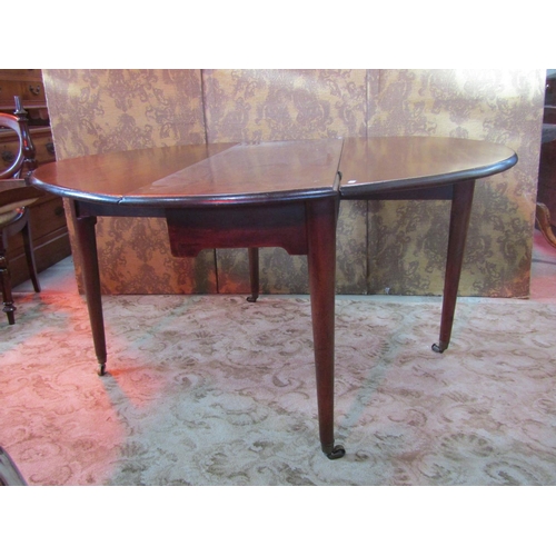 1250 - A Georgian mahogany oval dropleaf dining table raised on simple turned tapered legs with brass caps ... 