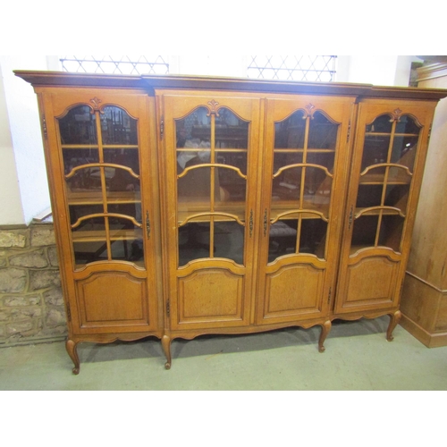 1281 - A continental shallow breakfront freestanding side cabinet enclosed by four glazed and moulded panel... 