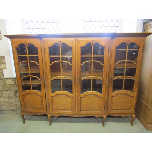 1281 - A continental shallow breakfront freestanding side cabinet enclosed by four glazed and moulded panel... 