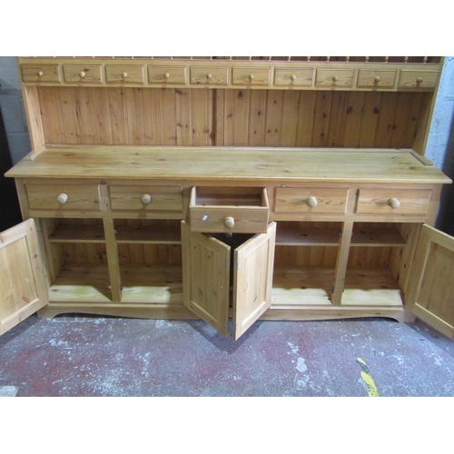 1354 - A large stripped pine kitchen dresser, the base enclosed by a T shaped arrangement of eight drawers,... 