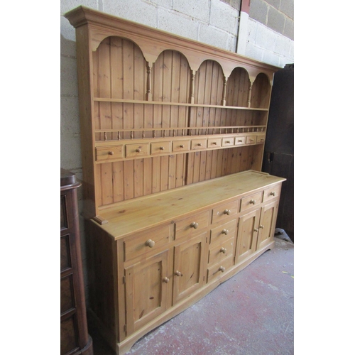 1354 - A large stripped pine kitchen dresser, the base enclosed by a T shaped arrangement of eight drawers,... 