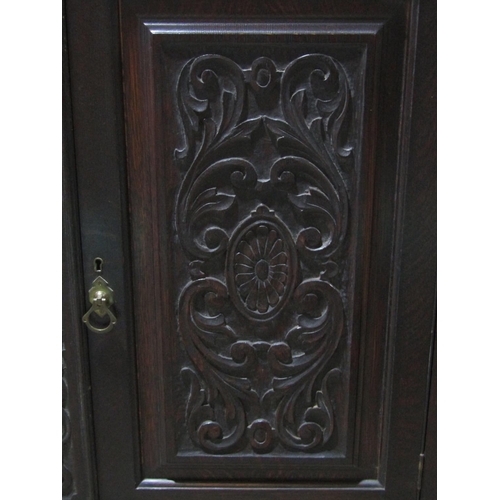 1387 - Edwardian oak cabinet enclosed by two carved and panelled doors with open framework on barley twist ... 