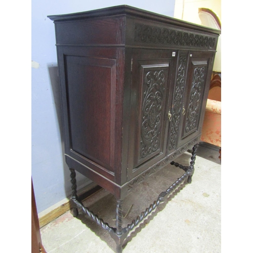 1387 - Edwardian oak cabinet enclosed by two carved and panelled doors with open framework on barley twist ... 