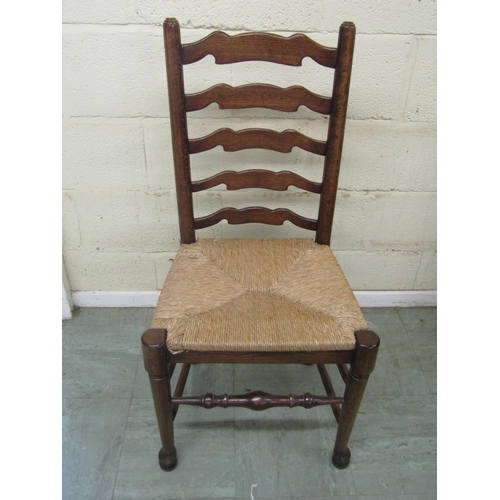 1399 - A set of six oak ladderback chairs (4+2) with rush seats and pad feet on turned supports