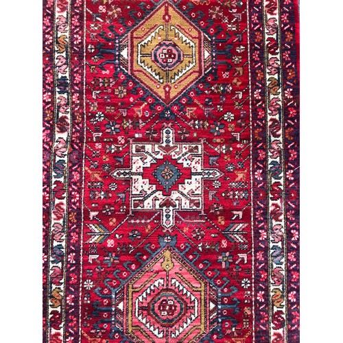 1582 - A Kadjar runner, Persian with medallion centre upon a red and floral field and within running border... 