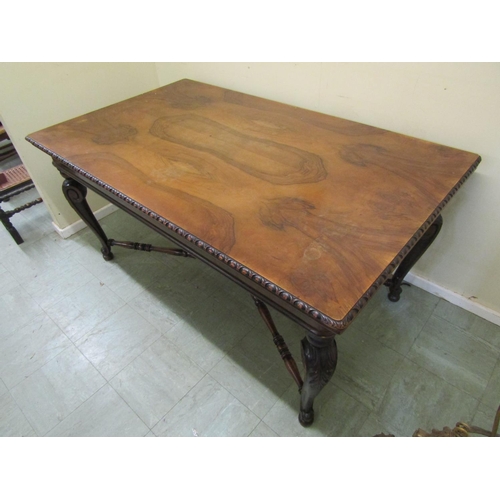 1399A - A walnut dining table of rectangular form with figured top and moulded edge raised on scrolled cabri... 