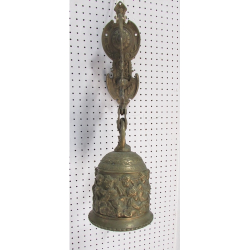 534A - A 19th century brass porch bell, decorated with cherubs and scrolling, hung from a wall mounted brac... 