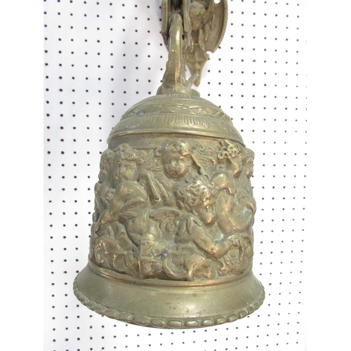 534A - A 19th century brass porch bell, decorated with cherubs and scrolling, hung from a wall mounted brac... 