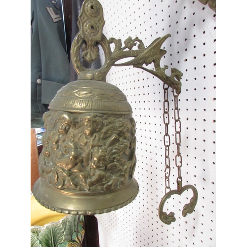 534A - A 19th century brass porch bell, decorated with cherubs and scrolling, hung from a wall mounted brac... 