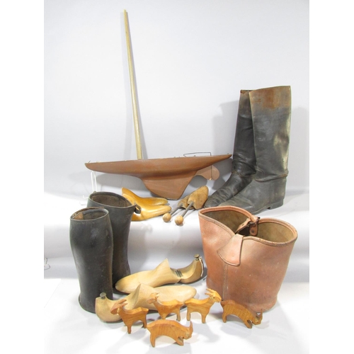 A pair of riding boots, pair of gaters, shoe lasts,  a leather bucket wooden cut out animals,  and a wooden hull of a yacht.