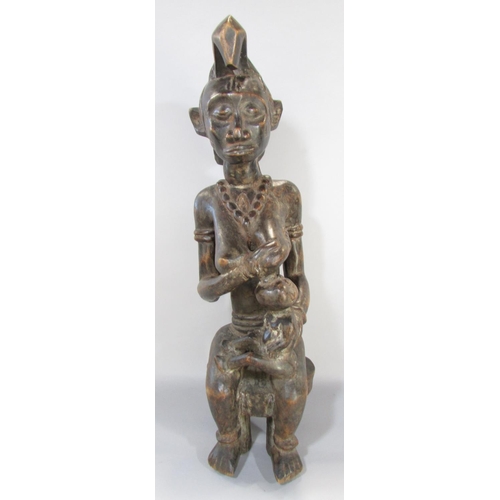 643A - An African carving in the Congolese style of a woman breast feeding a baby, 66cm high.