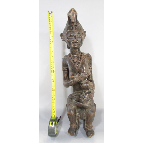 643A - An African carving in the Congolese style of a woman breast feeding a baby, 66cm high.