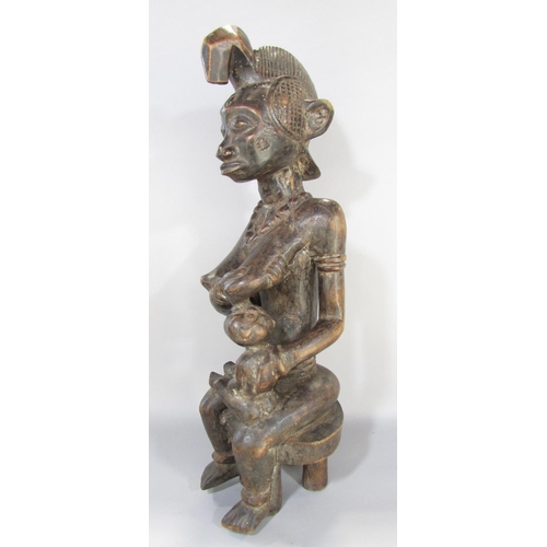 643A - An African carving in the Congolese style of a woman breast feeding a baby, 66cm high.