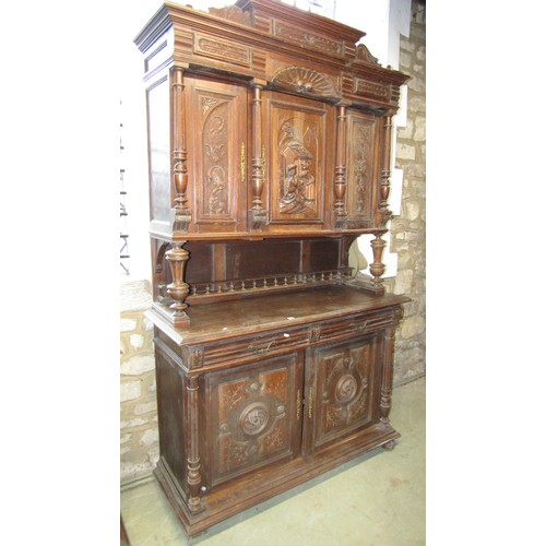 1293 - A continental oak buffet enclosed by an arrangement of cupboards and drawers with carved detail flan... 