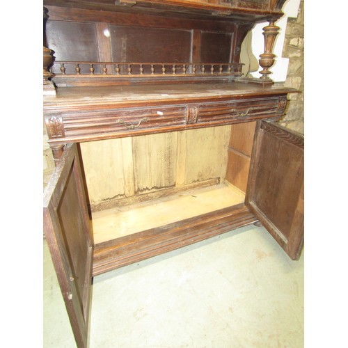 1293 - A continental oak buffet enclosed by an arrangement of cupboards and drawers with carved detail flan... 