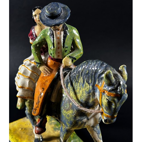 55 - A ceramic figure group in the form of a couple open horseback, ‘Flamencos A Caballo’, with hand pain... 