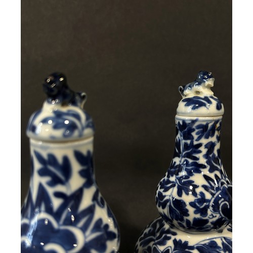51 - A pair of 19th century Chinese gourd shaped blue and white porcelain vases and covers with trailing ... 