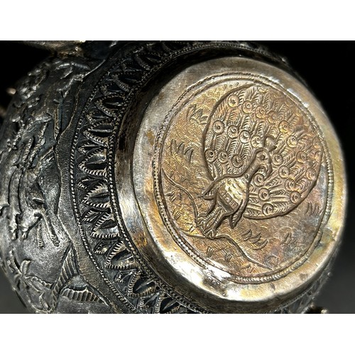 179 - A middle eastern silver metal bowl with cover and serpent handles decorated with lions, gazelles and... 