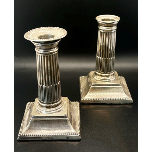 204 - A pair of small reeded silver column  candlesticks raised on a platform base (one lacking a sconce) ... 