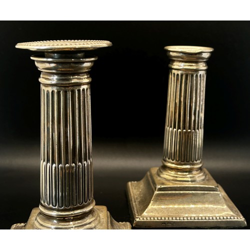 204 - A pair of small reeded silver column  candlesticks raised on a platform base (one lacking a sconce) ... 