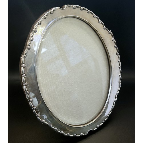 196 - An Edwardian oval silver picture frame, glazed with a silk back, Birmingham 1907, H.W. Ltd for Henry... 