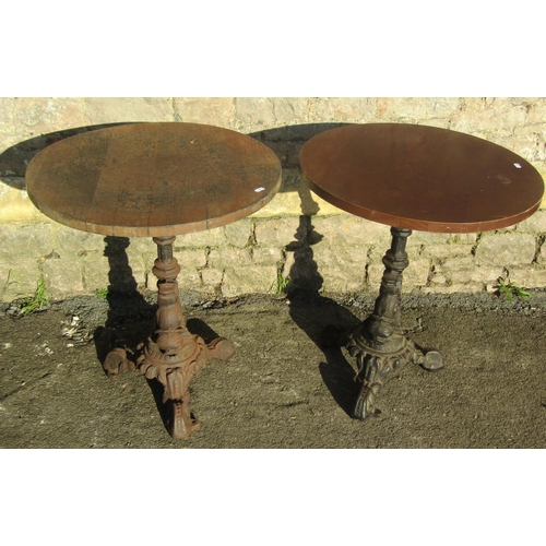 1070 - Pair of circular wooden topped pub tables raised on cast iron bases with entwined stylised dolphin d... 