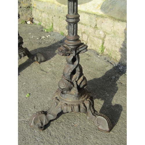 1071 - Pair of circular wooden topped pub tables raised on cast iron bases with entwined stylised dolphin d... 