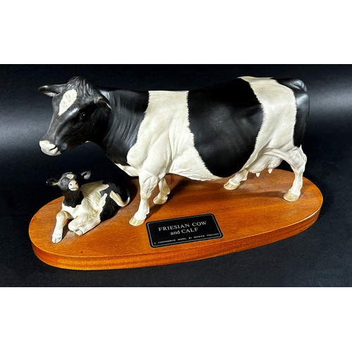 68 - A Beswick porcelain model of a Friesian cow & calf on oval timber base