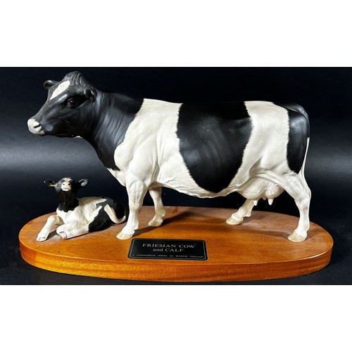 68 - A Beswick porcelain model of a Friesian cow & calf on oval timber base