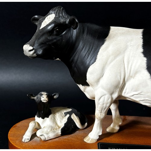 68 - A Beswick porcelain model of a Friesian cow & calf on oval timber base