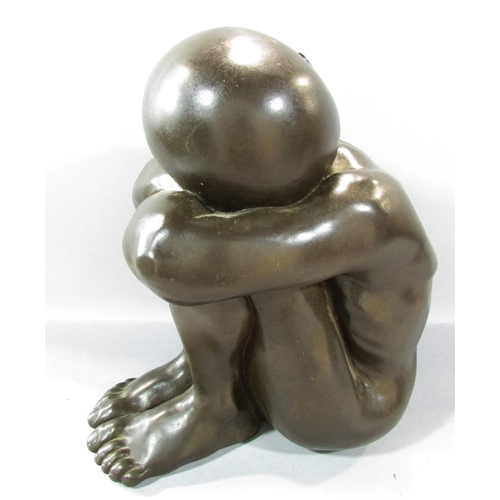 493 - A bronze effect resin study of a naked figure, sleeping on arms resting on drawn up knees, 34cm high... 