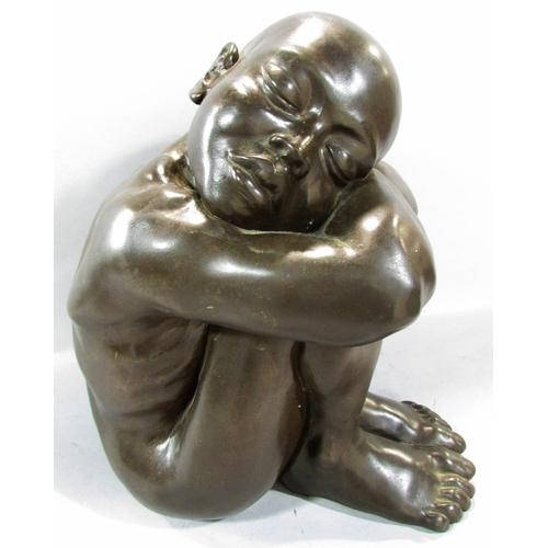 493 - A bronze effect resin study of a naked figure, sleeping on arms resting on drawn up knees, 34cm high... 