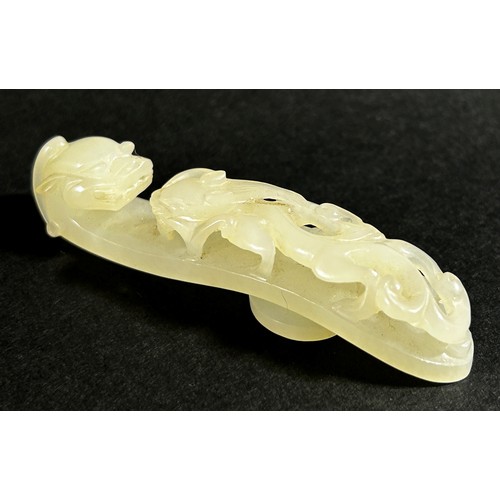 221 - A pale Chinese jade belt hook, decorated with pierced dragon mounts, 8cm long, Qing dynasty or later... 