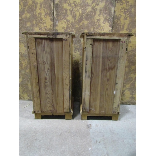 1075 - A pair of stripped and waxed pine bedside cabinets each enclosed by a panelled door and frieze drawe... 