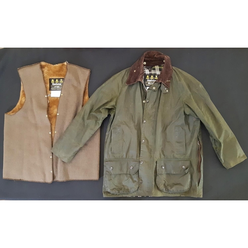 883 - A Barbour 'Beaufort' waxed jacket  in green with 2-way front zip, brown corduroy collar and numerous... 