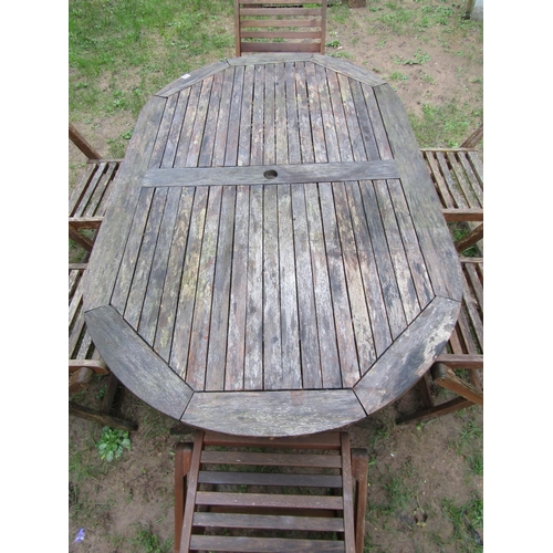 1035 - A weathered contemporary teak garden table of oval form with slatted top, raised on X framed support... 