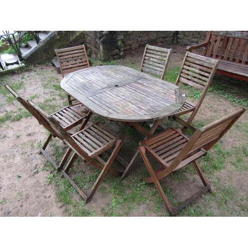 1035 - A weathered contemporary teak garden table of oval form with slatted top, raised on X framed support... 