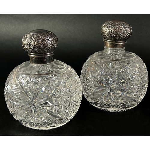 197 - A pair of cut glass dressing table bottles with silver floral engraved caps